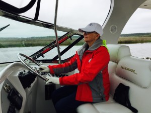 First Mate Ann takes a turn at the wheel.  Note jacket and gloves -- not exactly warm here, especially on the water.