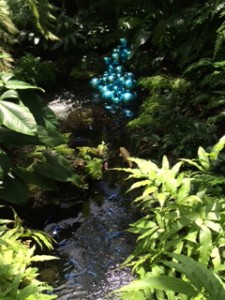 Here a collection of blue glass spheres is placed just above a pond filled with brilliant blue fish. 